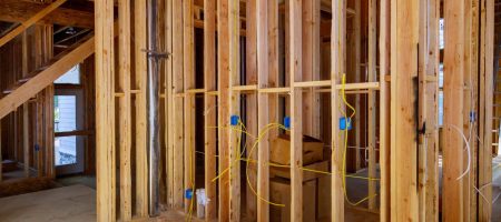 Electrician planning electrical wiring layout during a home remodel with exposed framing and modern residential construction