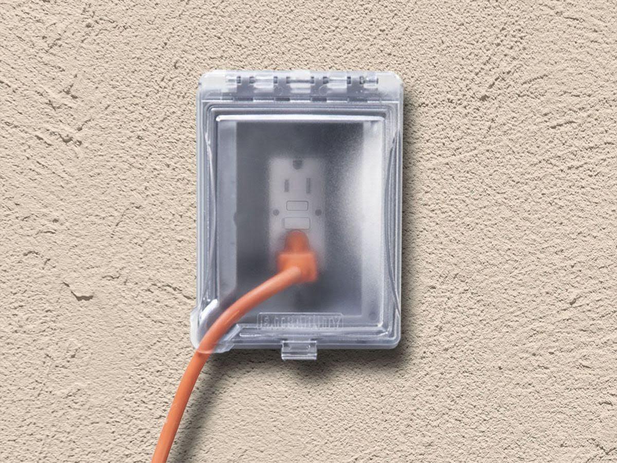 Outdoor GFCI electrical outlet with weatherproof cover safely powering equipment in backyard